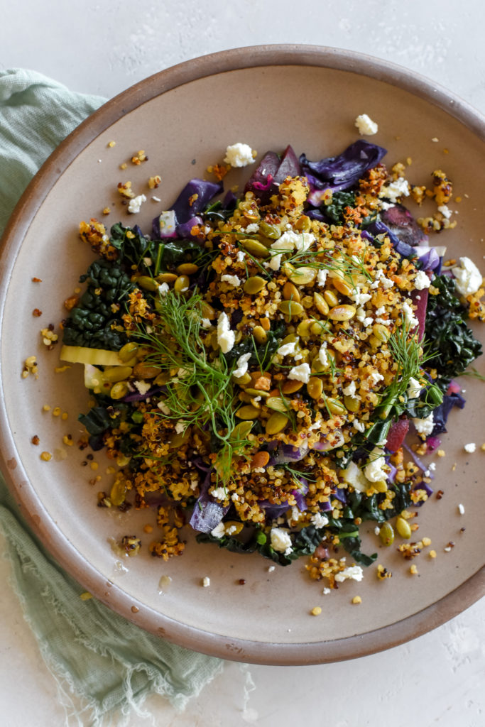 warm kale salad with crispy quinoa topping and crumbled feta
